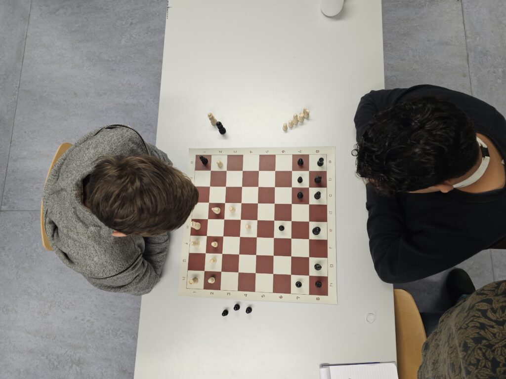 Twee jongeren spelen samen schaak tijdens een activiteit van Walk With Shark.