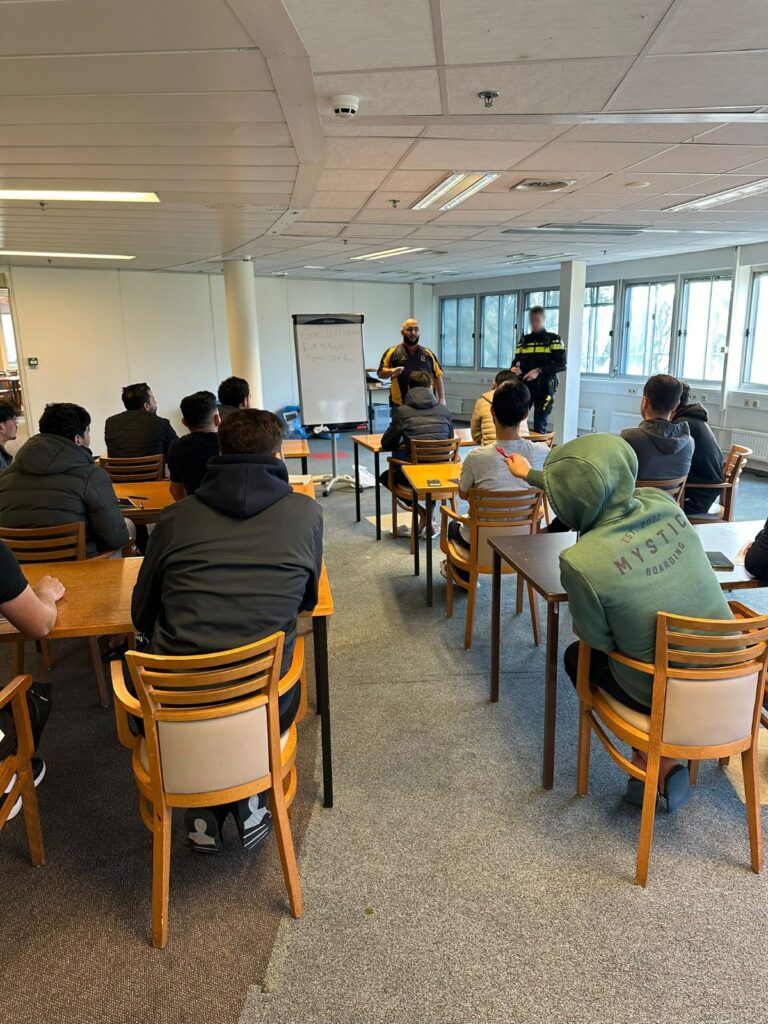KNM-les voor nieuwkomers op een COA- of ISK-locatie, gericht op veiligheid, participatie en taalontwikkeling.